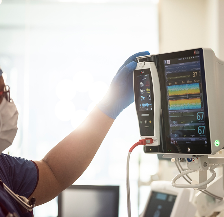Healthcare provider interacting with a Masimo patient monitoring system showing advanced vital sign trends.